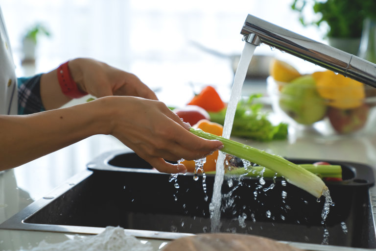 woman washing vegetables in sink