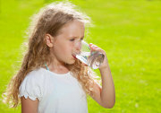 child drinking glass of water outdoors